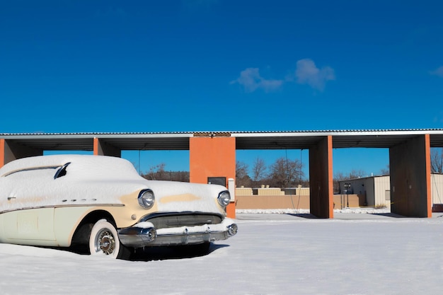 Antigo carro retrô vintage coberto e cercado por neve sob o céu azul