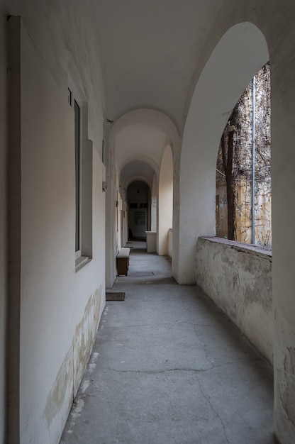 Antigo corredor residencial com grande arco e pintado de branco