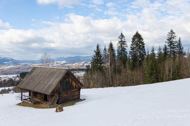 Antigo edifício de madeira decrépito em montanhas cobertas de neve