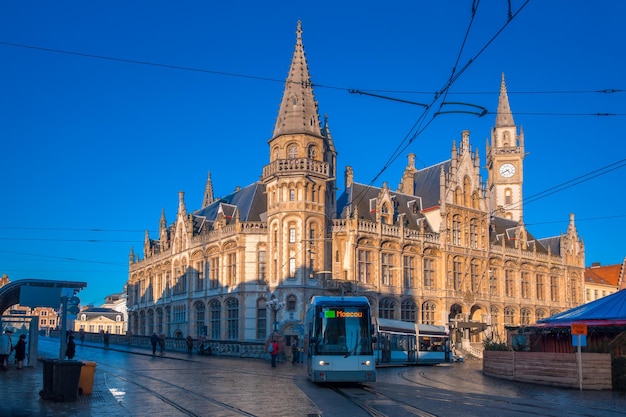 Antigo edifício dos correios, oude postkantoor, com torre do relógio em korenmarkt e bonde moderno da cidade na manhã ensolarada, ghent, bélgica