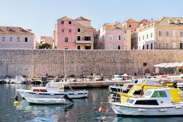 Antigo porto com pessoas e barcos no mar Adriático em Dubrovnik, Croácia.