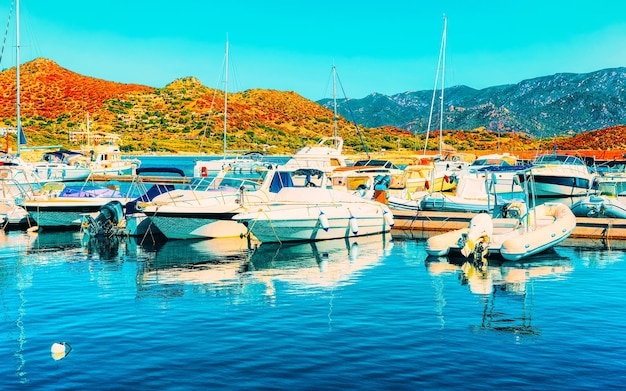 Antigo porto e marina da Sardenha com navios no mar Mediterrâneo, na cidade de Villasimius, na ilha da Sardenha do Sul, Itália, no verão. Arquitetura da cidade com iates e barcos