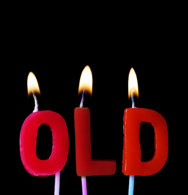 Antigo soletrado em velas de aniversário vermelhas contra um fundo preto