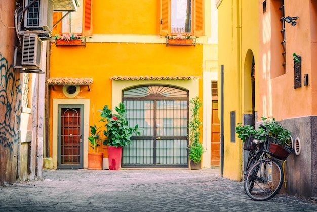 Antigua y acogedora calle en Trastevere, Roma, Italia con una bicicleta y una casa amarilla.