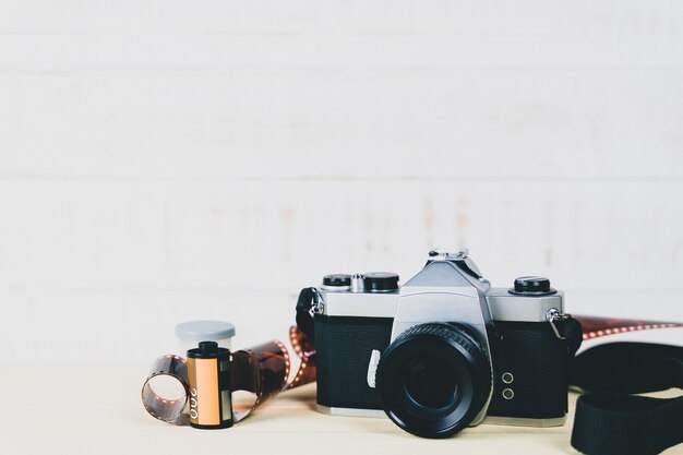 Foto antigua cámara de película slr de 35 mm y un rollo de película sobre fondo de madera. concepto de fotografía de flim.