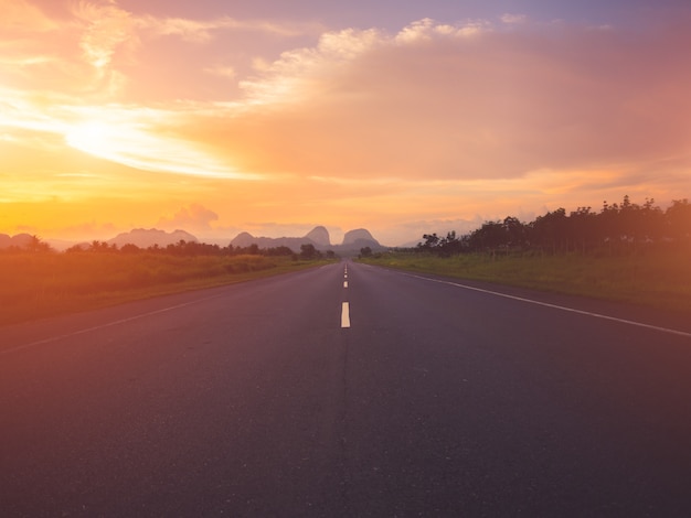 Antigua carretera contra montañas y un cielo nublado durante la puesta de sol.