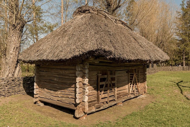 Una antigua casa de campo rural con techo de paja construida con troncos. Edificio tradicional ucraniano