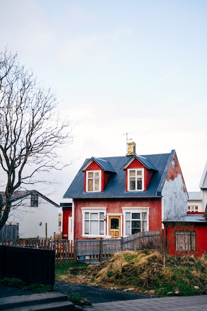 Antigua casa clásica roja con techo azul y ventanas en el techo en reykjavik, la capital de islandia