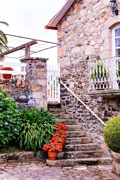 Antigua casa de piedra con una escalera con plantas en macetas y un hermoso balcón.
