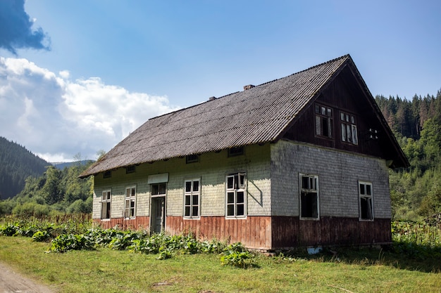 Antigua casa de pueblo abandonada rodeada de bosque verde en las montañas de los Cárpatos, Burkut, Ucrania