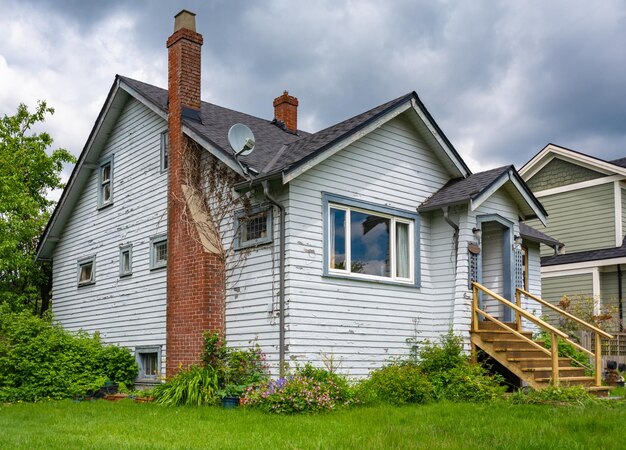 Antigua casa residencial con chimenea de ladrillo y césped descuidado en el frente