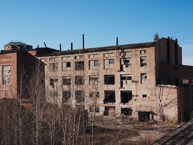 Una antigua fábrica abandonada a principios de otoño. trasfondo post-apocalíptico. Edificios que se derrumban.