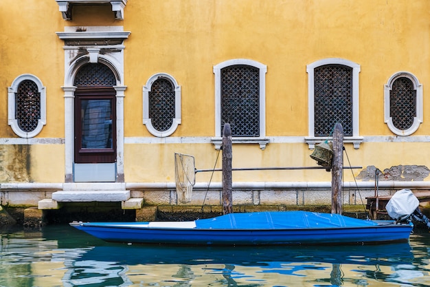 Foto antigua fachada amarilla y lancha en el canal de la ciudad de chioggia en véneto, italia