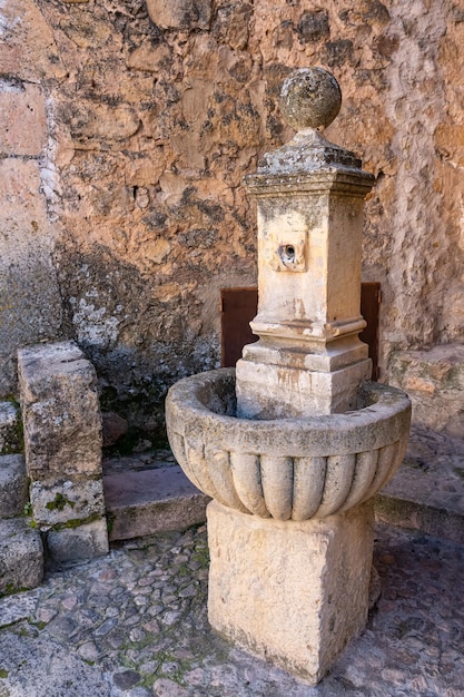 Antigua fuente de piedra para dar agua a los transeúntes en la calle del pueblo medieval de Pedraza Segovia