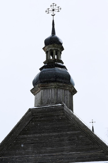 Antigua iglesia de madera hecha de troncos redondos Cruz en la cúpula Paisaje ruso de invierno Árboles cubiertos de nieve Antigua aldea rusa abandonada cubierta de nieve