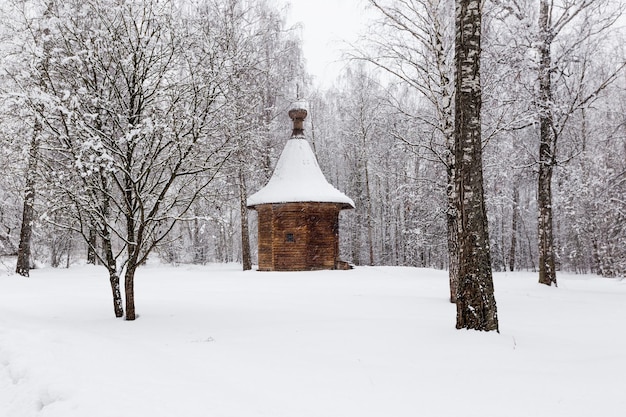 Antigua iglesia ortodoxa de madera con múltiples cúpulas o capilla, monumentos de arquitectura invernal durante una nevada en Rusia