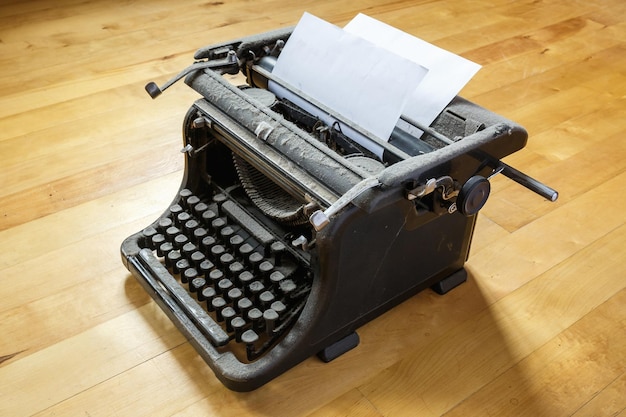 Antigua máquina de escribir cubierta de polvo vintage con hoja de papel blanco