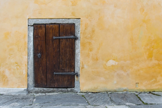 Antigua puerta de madera pequeña en la pared rústica amarilla
