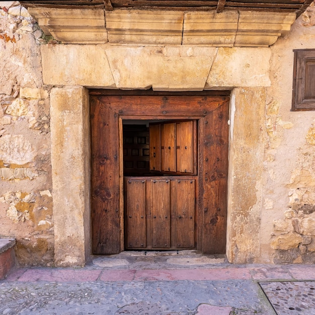 Antigua puerta de madera que se abre en dos partes en las casas de piedra del pueblo medieval de Pedraza Segovia