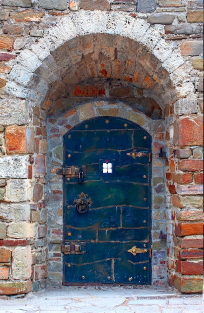 La antigua puerta de metal con mampostería de piedra con cerradura