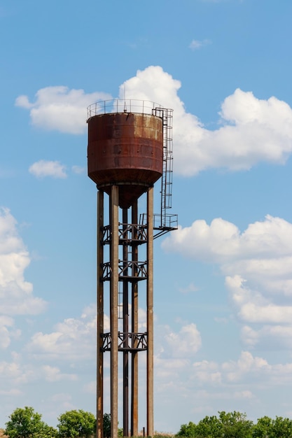 Antigua torre de agua oxidada en el campo verde