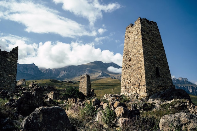 Antigua torre de piedra en terreno montañoso verde Antiguo edificio de piedra del casco antiguo situado en una colina verde contra montañas cubiertas de bosque y niebla en verano