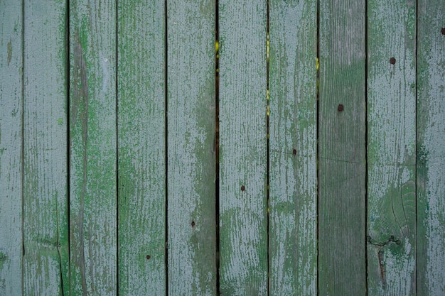 antigua valla de madera pintada con pintura verde agrietada por el tiempo