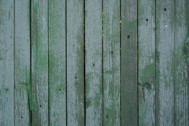 antigua valla de madera pintada con pintura verde agrietada por el tiempo