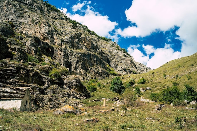 Antiguas casas de piedra en montañas verdes Increíble paisaje con edificios de piedra envejecidos ubicados en la ladera de hierba verde de la montaña rocosa en un día soleado de verano