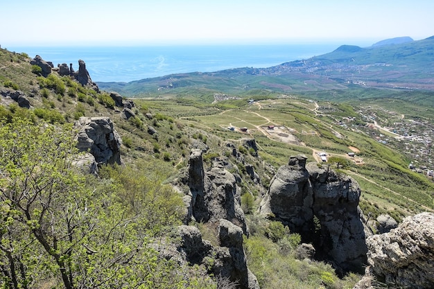 Antiguas montañas altas de piedra caliza de forma redondeada en la neblina de aire. El Valle de los Fantasmas. Demerji. Árboles y arbustos verdes en primer plano. Mayo de 2021. Crimea.