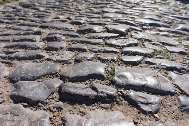 Antiguas piedras irregulares en una carretera pavimentada