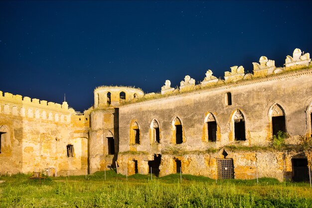 Antiguo castillo medieval en la noche bajo un cielo azul oscuro con muchas estrellas