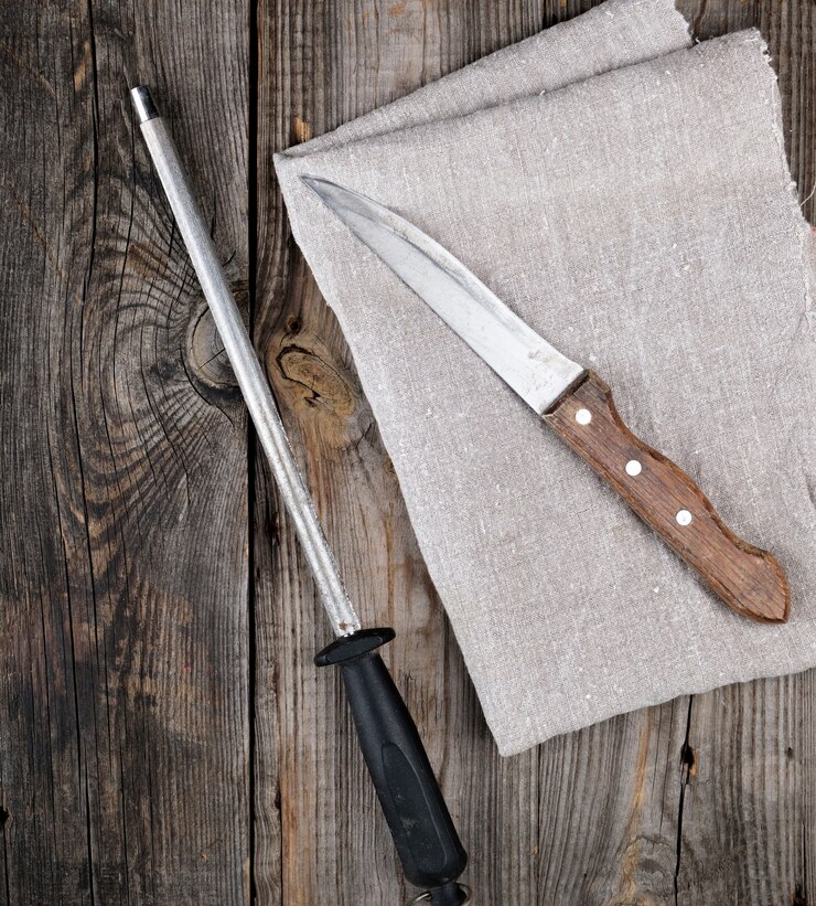 Foto antiguo cuchillo afilado y sacapuntas con un mango sobre un fondo de madera gris