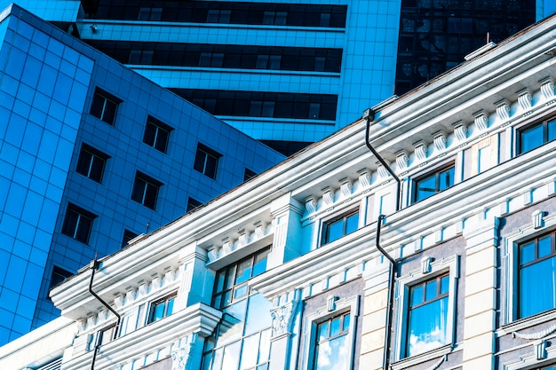 Un antiguo edificio al lado de un moderno edificio de oficinas. imagen abstracta de formas modernas e históricas de edificios