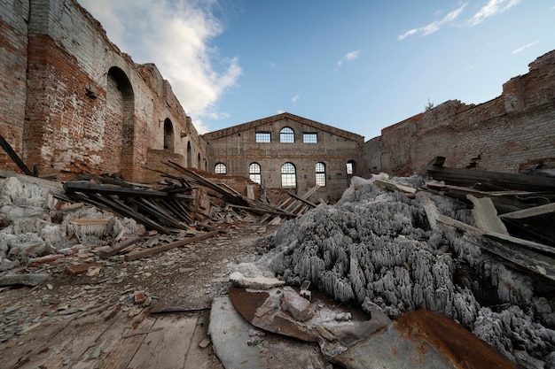 Antiguo edificio de ladrillo en ruinas, paredes. Sin techo, bajo un cielo azul abierto. montones de basura en el interior.