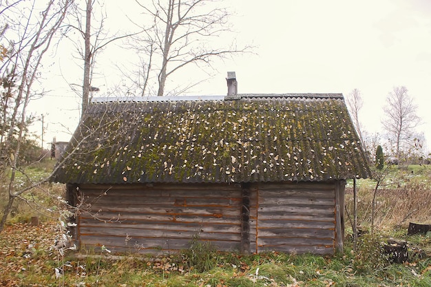 Antiguo edificio de madera de la casa de baños en el pueblo en el campo con hojas de otoño. Exterior tradicional de estilo ruso.
