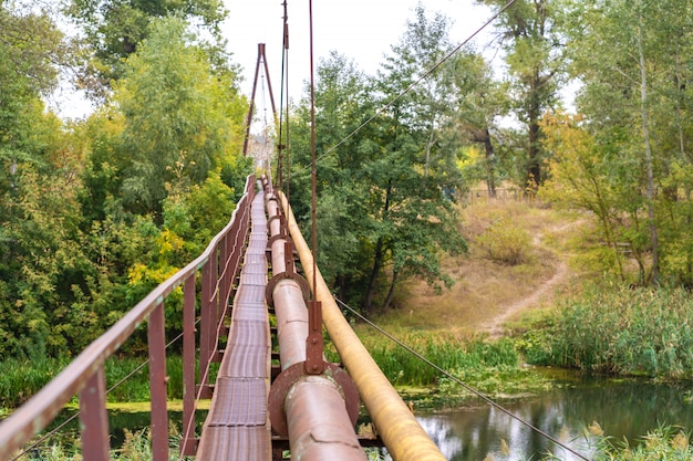 Un antiguo y estrecho cruce de río oxidado, junto con una tubería de agua y gas. Comunicaciones en el pueblo.