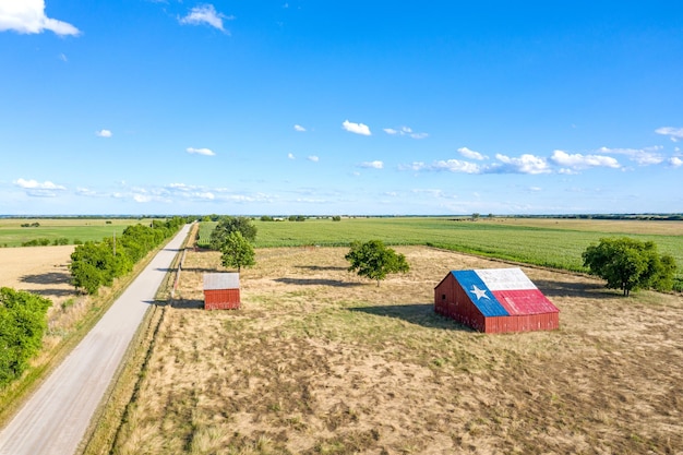 Un antiguo granero abandonado con el símbolo de Texas pintado en el techo se encuentra en una zona rural del estado enmarcada por tierras de cultivo