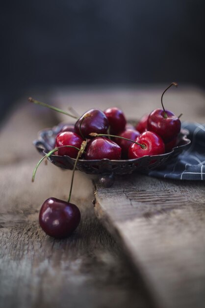 Antiguo jarrón vintage con cerezas frescas sobre fondo de madera vieja