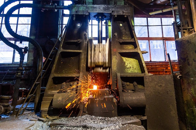 Antiguo martillo de vapor de trabajo en fábrica forja pieza de acero caliente con chispas