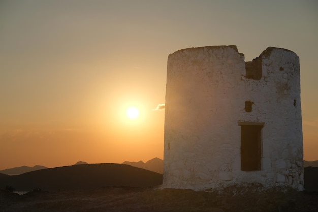 Antiguo molino de viento al atardecer contra el cielo, silueta de un antiguo molino en ruinas