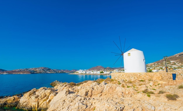 Antiguo molino de viento blanco en el acantilado frente al agua Grecia