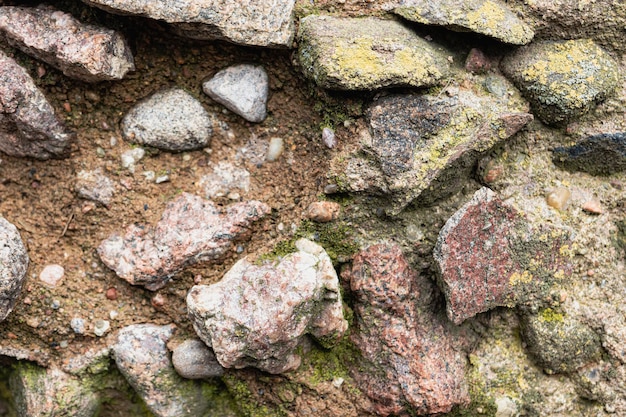 Antiguo muro de piedra de granito texturizado de grandes piedras grises cubiertas de musgo como fondo