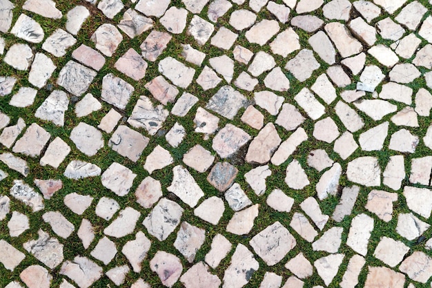 Antiguo pavimento de adoquines portugueses típicos con hierba que crece entre las piedras Lisboa Portugal