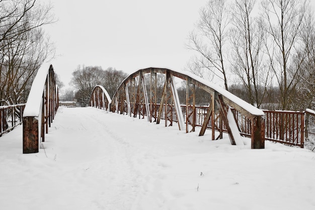 Antiguo puente de carretera de acero sobre el río después de las nevadas