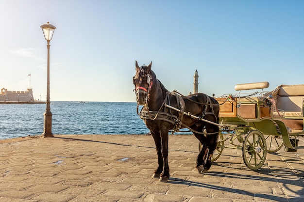 El antiguo puerto de la ciudad de Chania con carruaje tirado por caballos y faro en la isla de Creta, Grecia.
