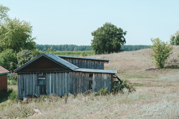 Un antiguo refugio de montaña de madera en un prado verde con árboles y cielo de fondo