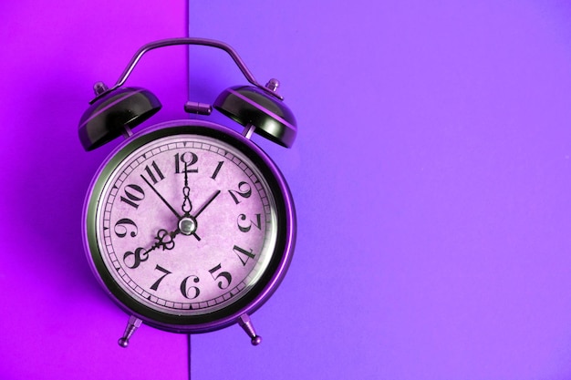 Antiguo reloj despertador retro vintage sobre un fondo lila púrpura brillante.