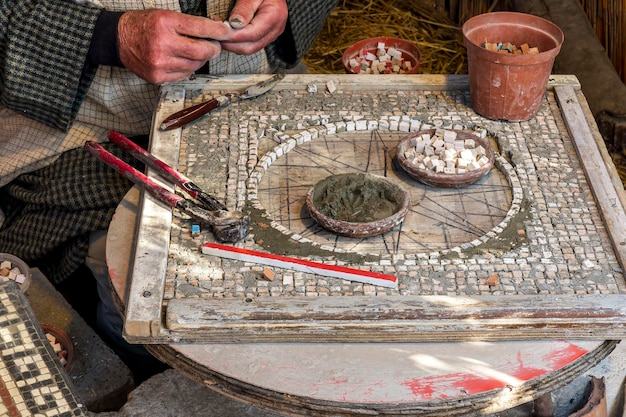 Antiguo taller vintage de artesanos de mosaicos con manos artesanales haciendo trabajo diario en un antiguo estilo rústico