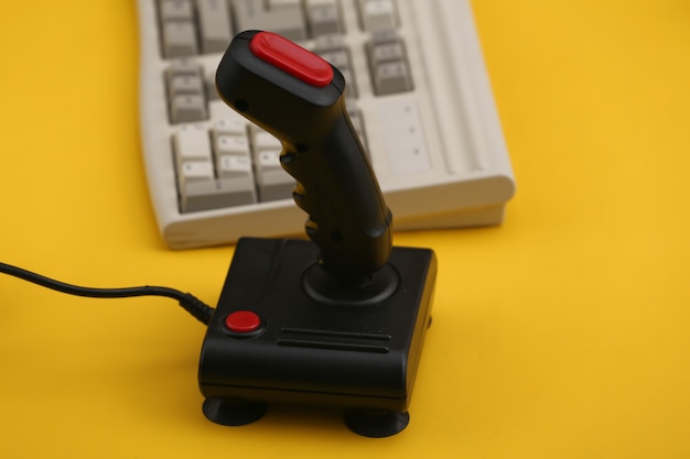 Antiguo teclado de pc y joystick sobre fondo amarillo. Juegos retro. Años 80.